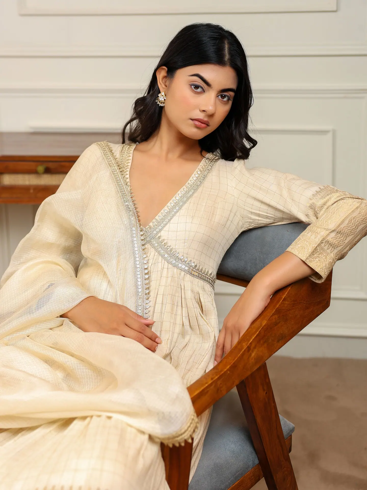 Champagne anarkali, seated with arm over the chair