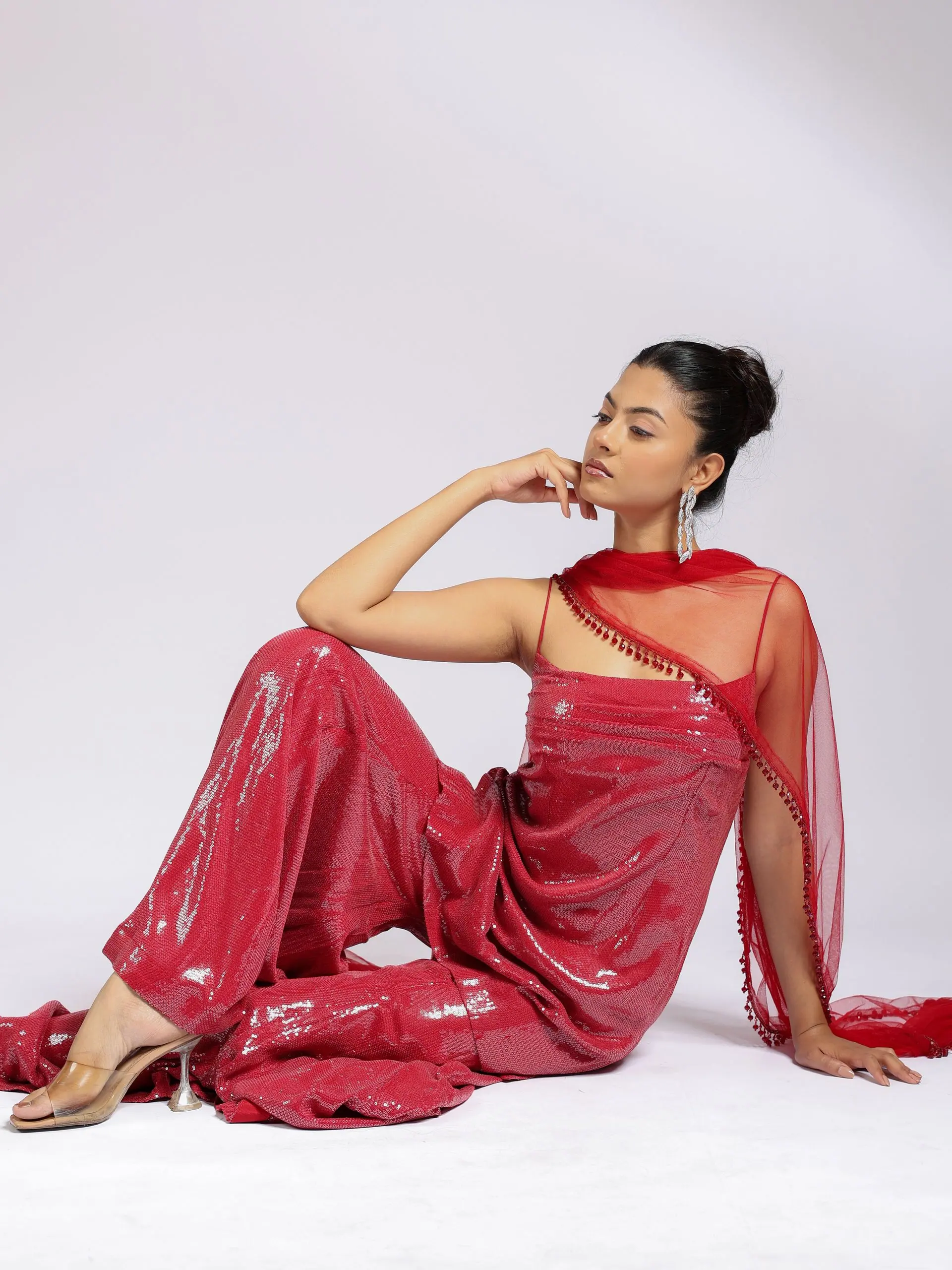 Model reclining in the crimson sequin sharara set