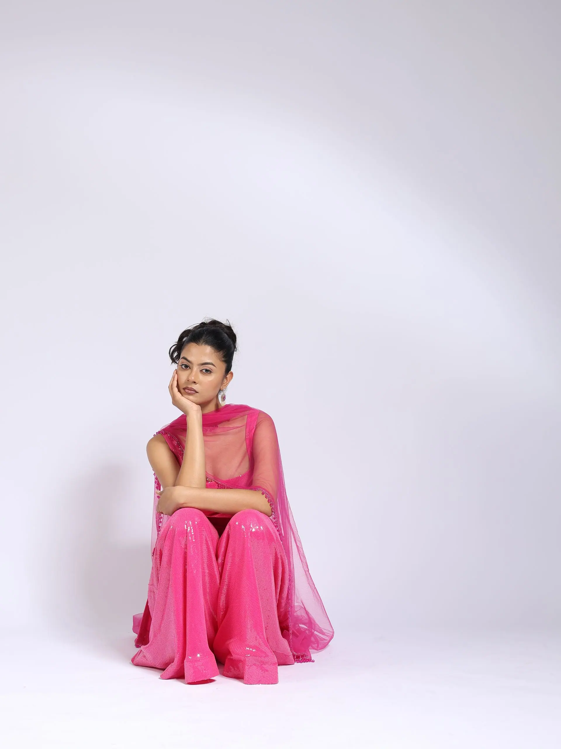 Model seated in the hot-pink sequin set on a studio floor