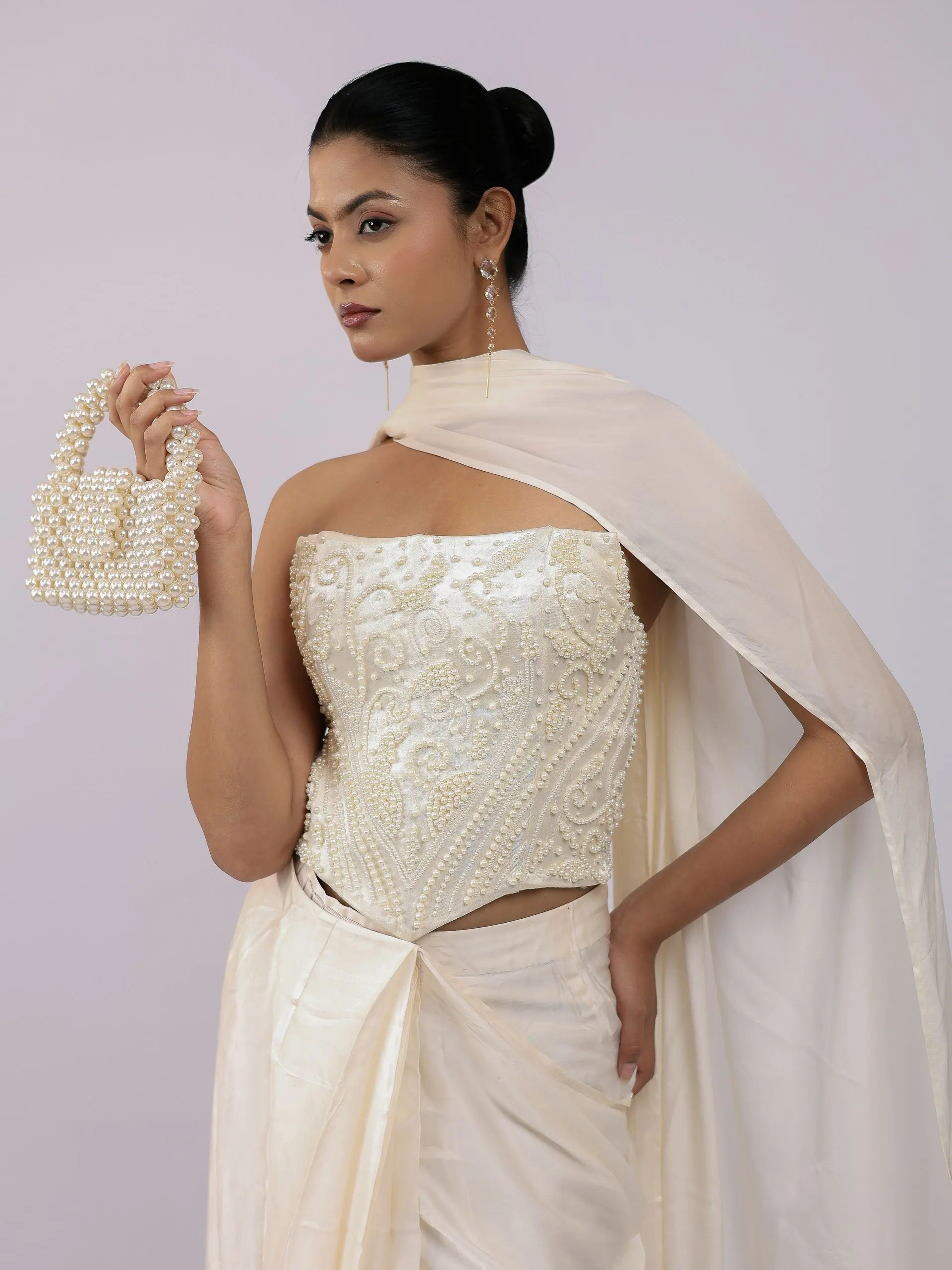 Ivory corset and draped skirt with a pearl bag, waist-up