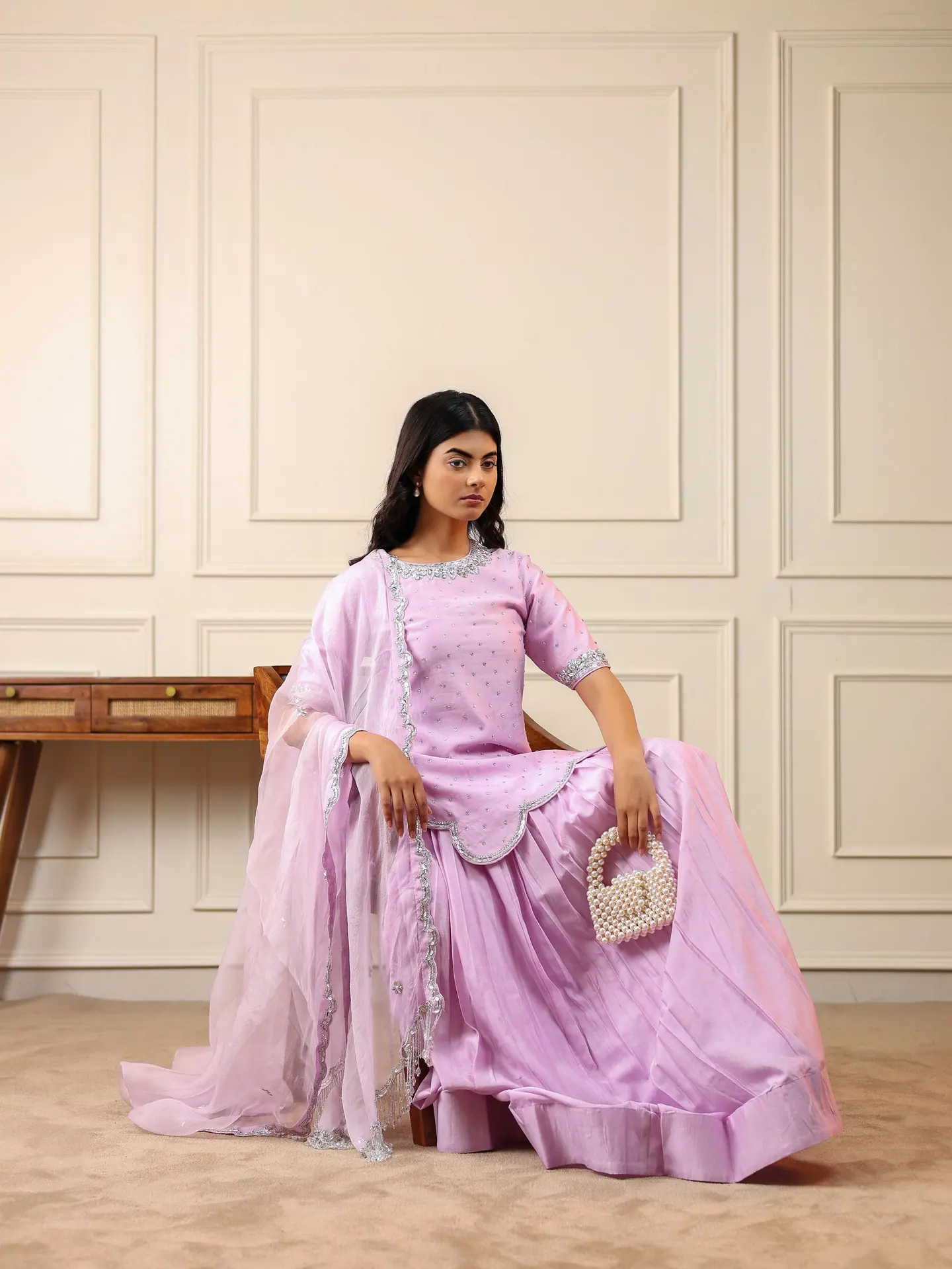 Lilac anarkali with silver-edged organza dupatta, seated by a cane desk