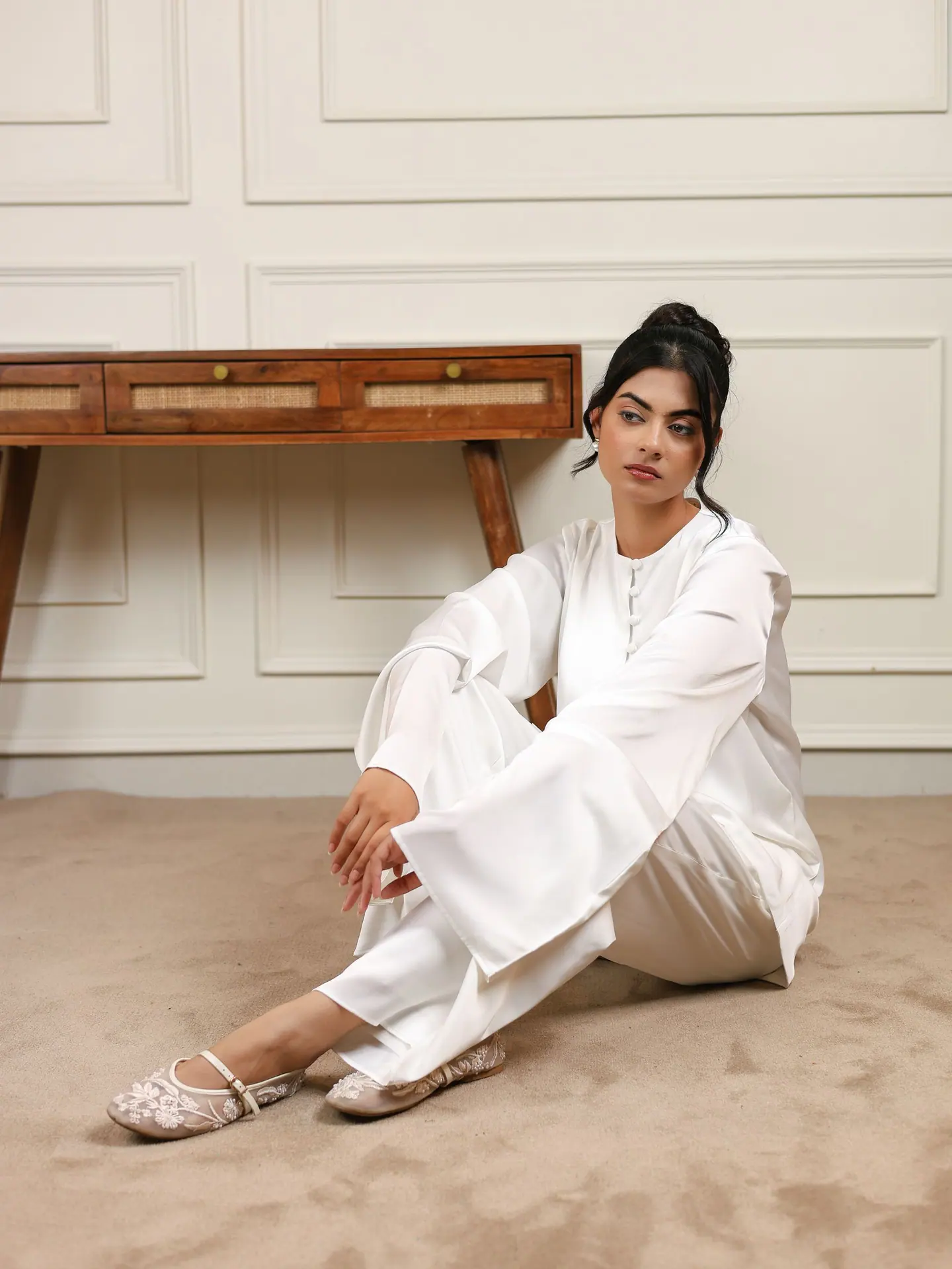 White satin co-ord, seated on the floor