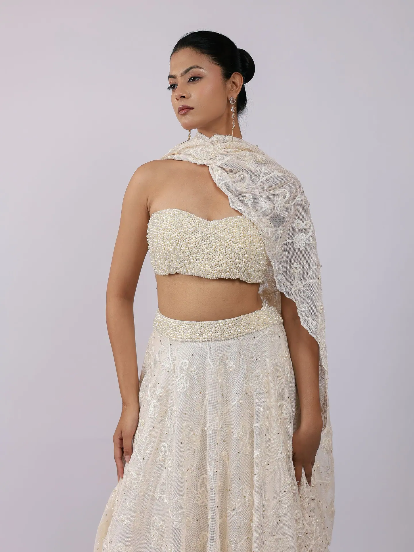 Pearl bustier and ivory lehenga with dupatta over the shoulder