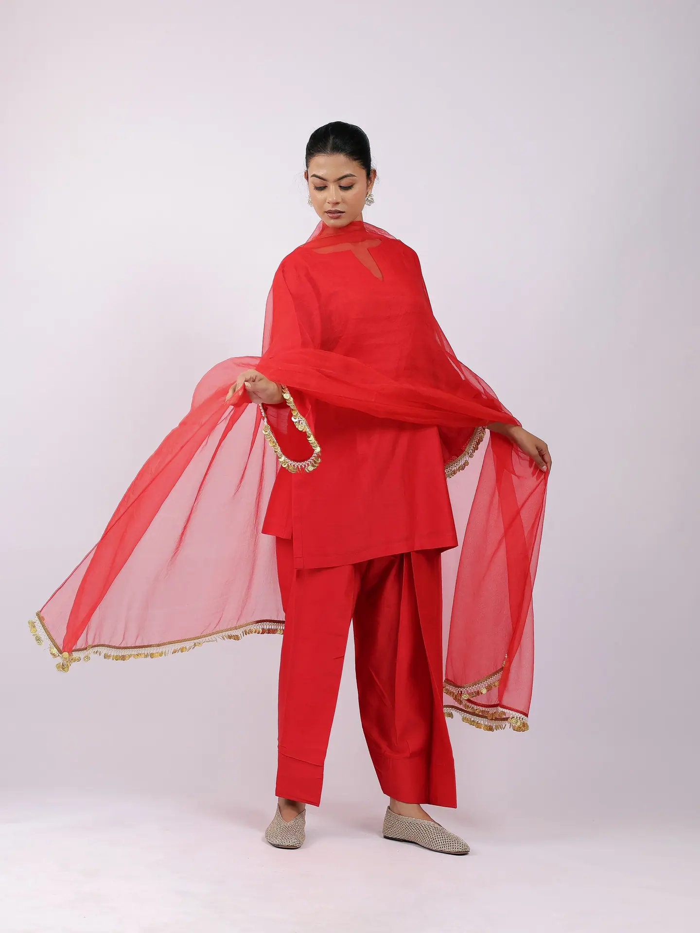 Scarlet kurta set with an organza dupatta held wide, full length